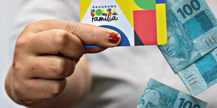 Cartão do Bolsa Família sendo segurado, com notas de R$ 100, representando os pagamentos do programa em 2025.