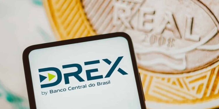 Tela de celular exibindo o logo do DREX, moeda digital do Banco Central do Brasil, com moedas ao fundo.