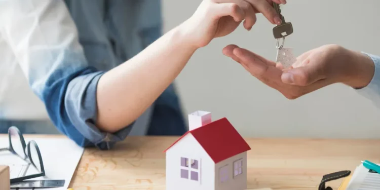 Pessoa entregando chave de casa para outra pessoa, simbolizando aquisição de imóvel.