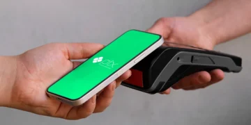 Pessoa fazendo pagamento por aproximação com o celular usando PIX em um terminal de pagamento.