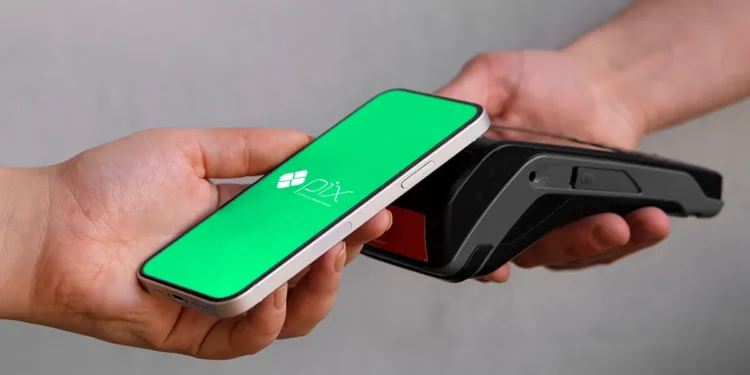 Pessoa fazendo pagamento por aproximação com o celular usando PIX em um terminal de pagamento.